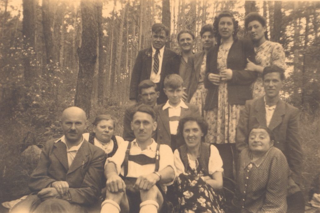 Gruppenporträt mit Männern, Frauen und Kindern im Wald.