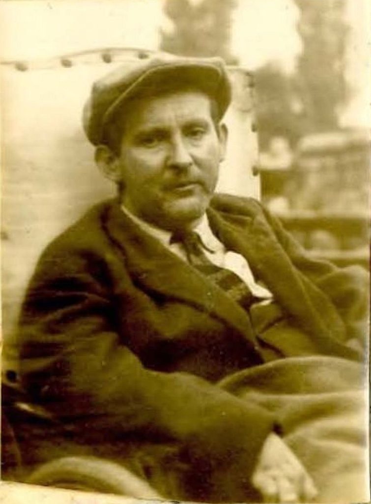 Der ca. 40-jährige Siegfried Braun, im Anzug und mit Kappe, sitzt im Rollstuhl und blickt direkt in die Kamera.